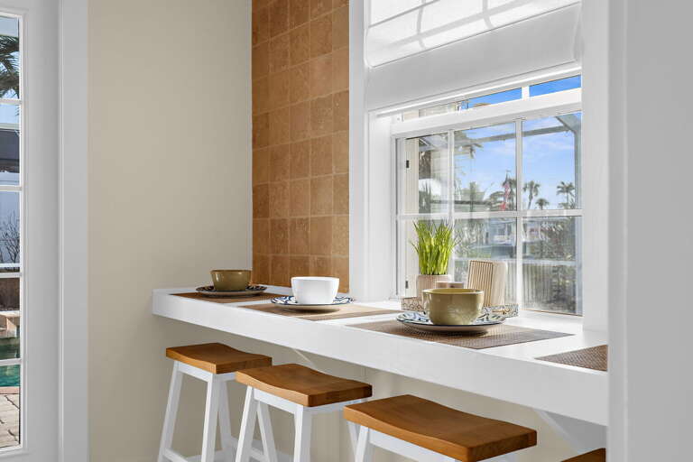 Sit at the breakfast bar and watch the pool through the window while your coffee goes warm — three wood stools, a granite counter, and zero reason to rush toward anything at all.