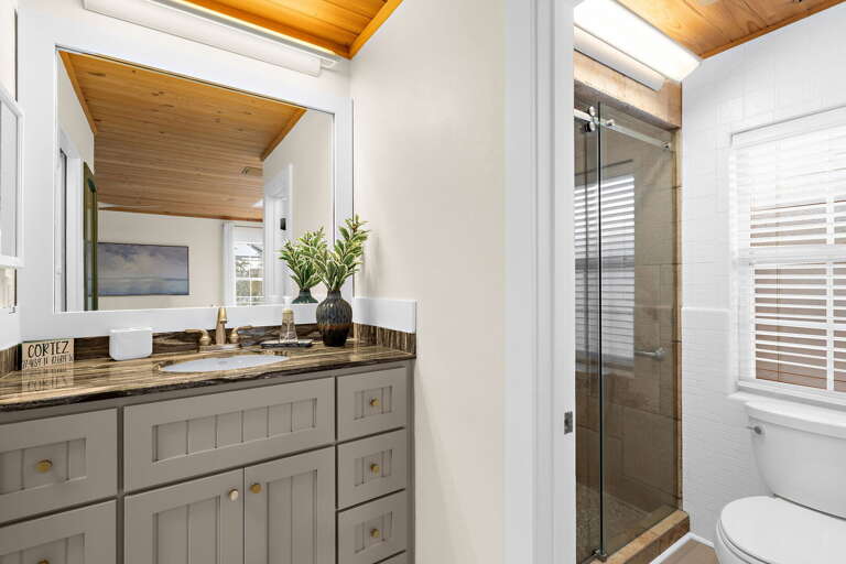 Start your morning in the glass-enclosed shower — dark granite, warm wood ceiling, and enough water pressure to wash off a full day on the water in about three minutes flat.