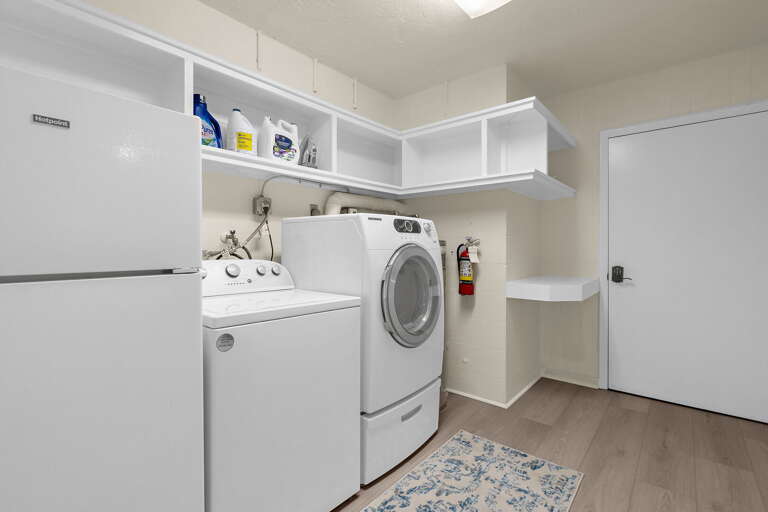 In-unit laundry room featuring full-size washer/dryer, extra fridge, and ample storage shelving