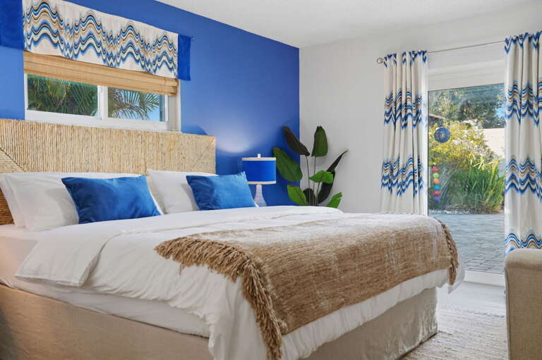 Dive into paradise! Our stunning cobalt-blue primary suite brings the ocean indoors, with plush linens and a private slider straight out to the lush garden patio.