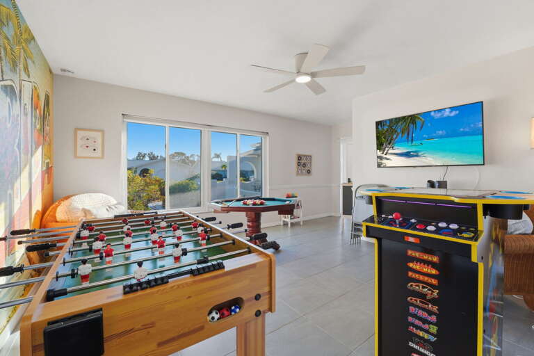 Pick your game — foosball one end, Pac-Man the other, pool table in the middle, and a TV overhead for whoever needs a break.