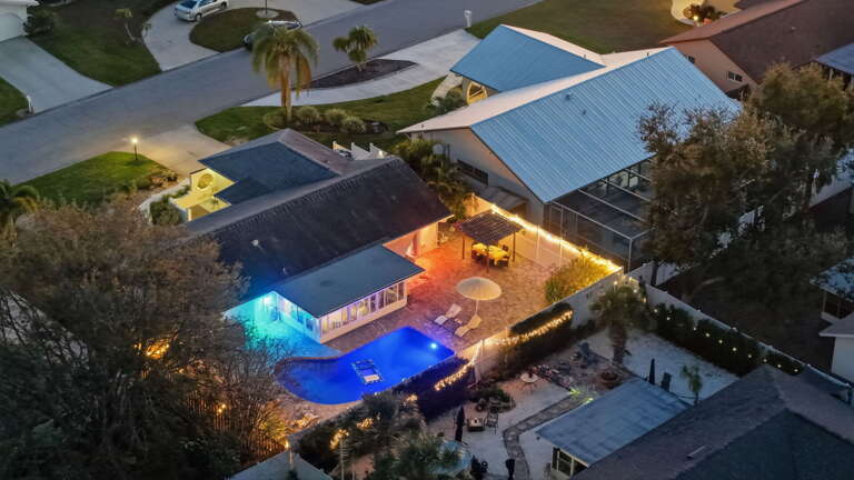 Stunning aerial view of the backyard oasis, pool, and twinkle-lit patio at twilight