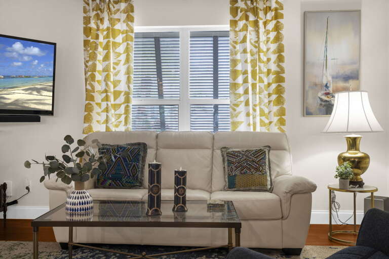 Kick back into the sofa — sailboat art on the wall, gold lamp lit, the kind of coastal living room that feels like it was styled just for this trip.