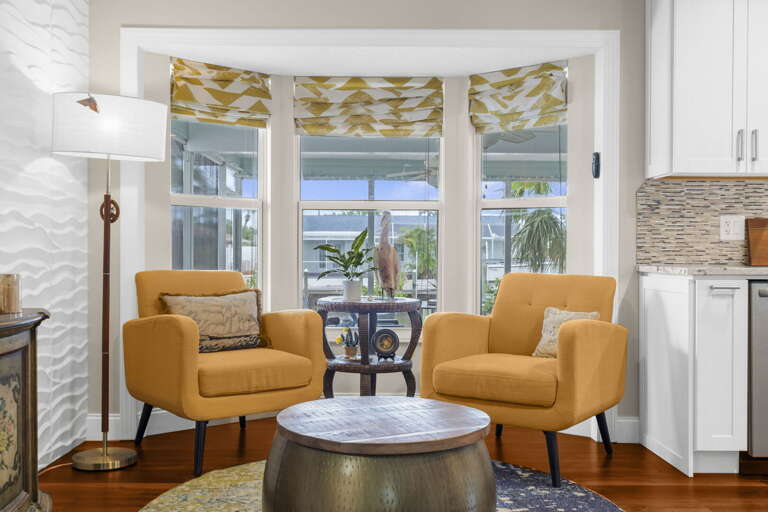 Your morning spot — two chairs, good light, and a view through to the screened porch and the canal beyond.