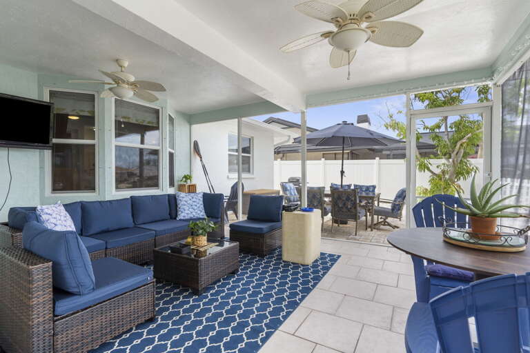 Your outdoor living room: sectional for six, outdoor TV, ceiling fans, dining table under the umbrella — the spot you'll spend half your trip.