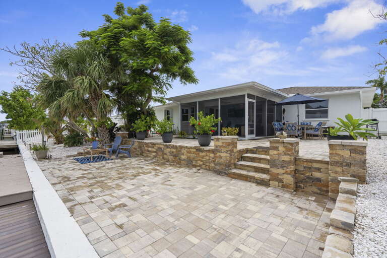 Step back and take in the full backyard from the canal — paver patio, screened lanai, and your private dock all connected and ready.