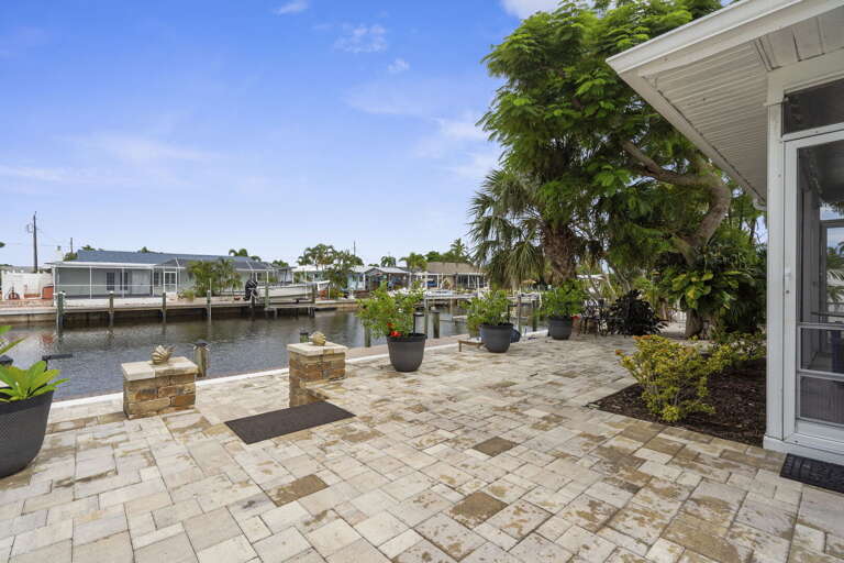 Walk out the back and you're already at the water — paver path, palm trees, and the canal right there.