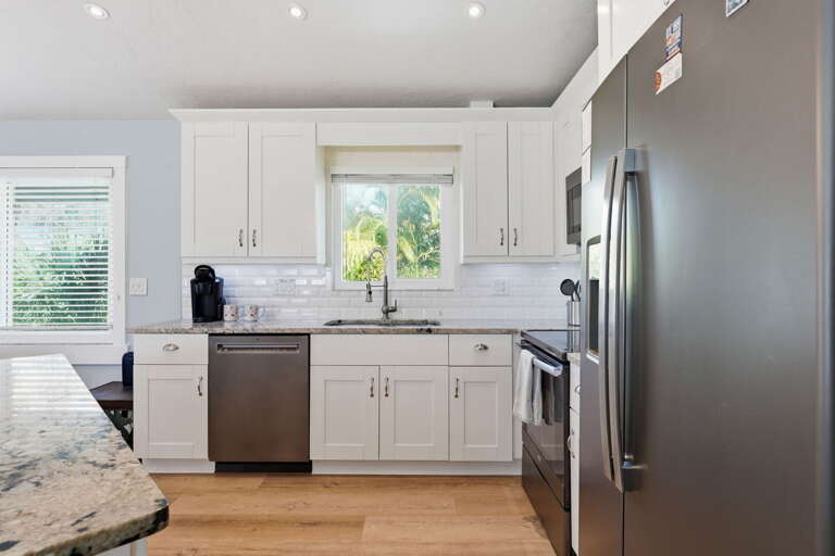 Cook with white shaker cabinets around you, subway tile behind, and a window over the sink keeping things bright.