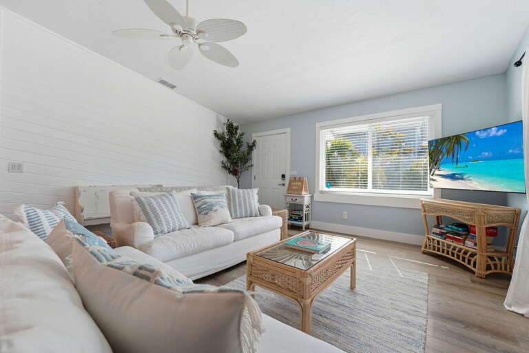 Find your own corner in this casual living room — white sofa, loveseat, Smart TV, and a big window letting in natural light.