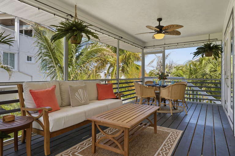 Hang out on the screened porch all evening — wide enough for the whole group with hanging ferns and palm tree views on every side.