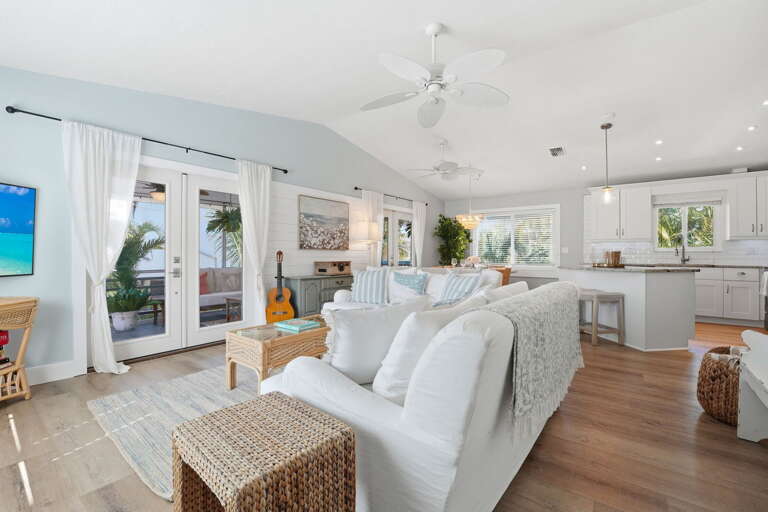 Come together in the main living area — white slipcovered sofas, vaulted ceiling, and the kitchen just steps behind you.