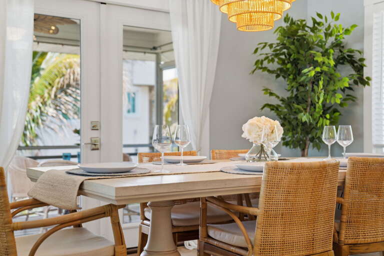 Pour the wine and take your seat — table set with white plates, glasses ready, and a gold woven chandelier glowing overhead.
