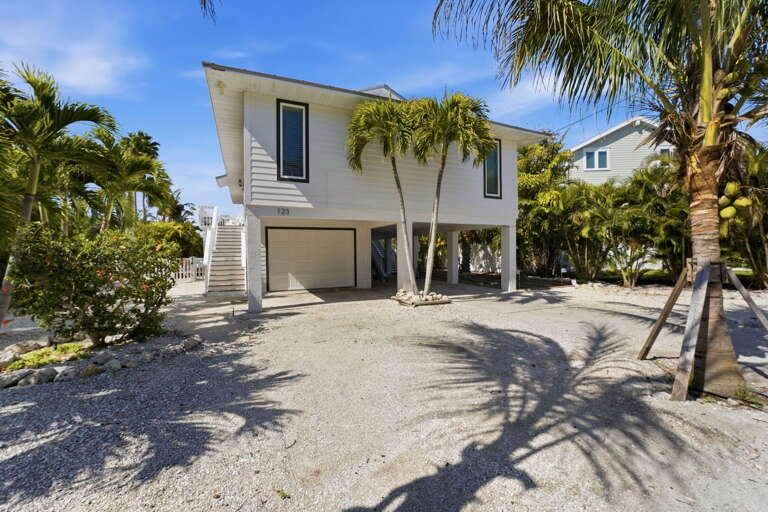 Pull into the gravel driveway and feel the island energy hit you — elevated home, palm trees, and the beach just .5 miles away.