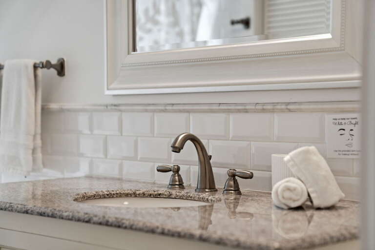 Roll out fresh towels at the second bath vanity — granite countertop, brushed nickel fixtures, and subway tile all around.