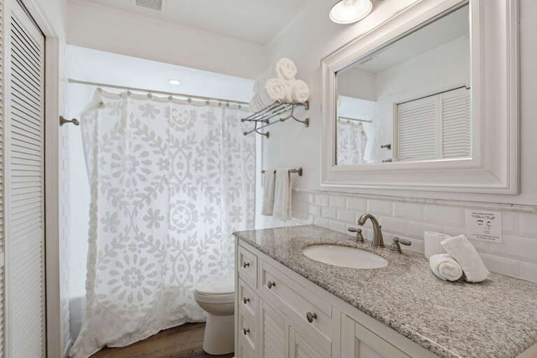 Use the shared second bathroom with ease — shower-tub combo, subway tile, framed mirror, and white vanity all clean and well-stocked.