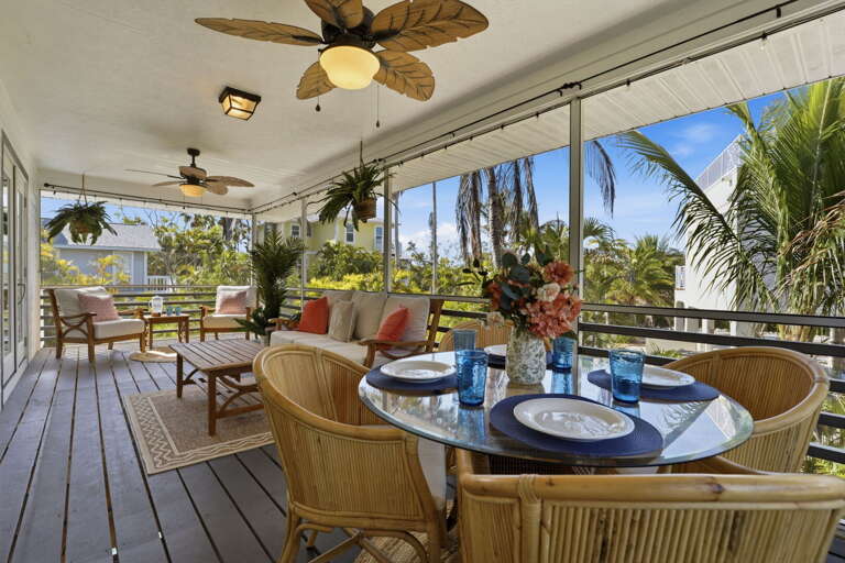 Sip your morning coffee here or wind down with a glass of wine — the screened porch catches every breeze while palm trees frame the view.