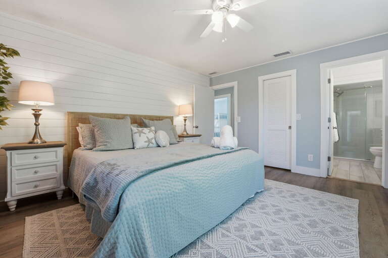 Sleep in the king master suite with a blue quilt, two nightstands with lamps, and your private ensuite bathroom steps away.