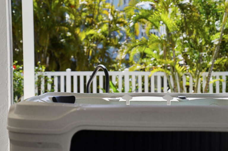 Soak while the jets run — the hot tub stays heated year-round and tropical greenery closes in around you.