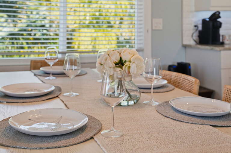 Toast the evening with wine glasses already in place — fresh flowers centered on the farmhouse table, good company around you.