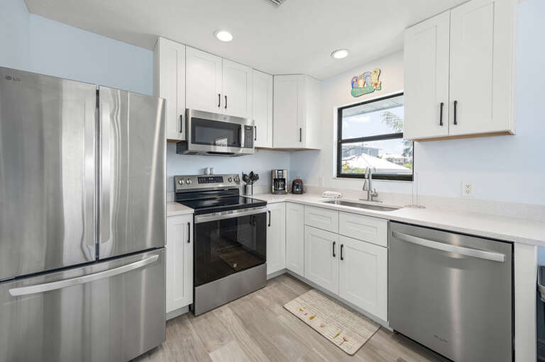 Find the whole appliance suite in a clean kitchen layout — natural window light above the sink, nothing missing.