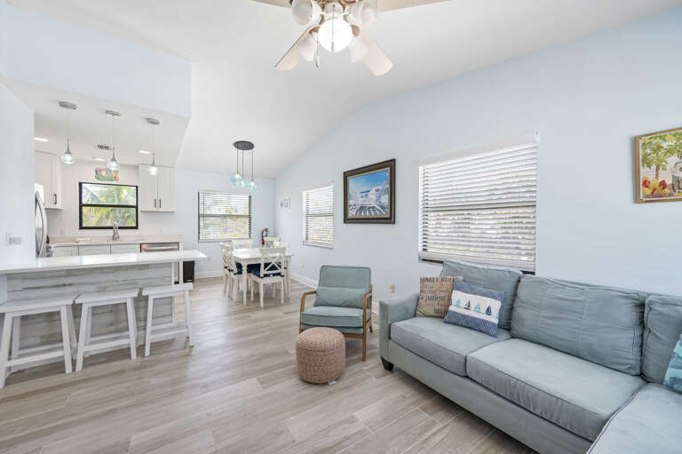 Gather the whole group here — sofa, accent chair, kitchen visible behind you, and the dining table just around the corner.