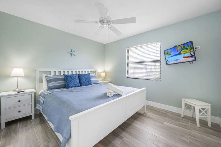 Unpack in the primary bedroom — king bed, wall-mounted TV, and two nightstands mean you're settled in, not just camping.