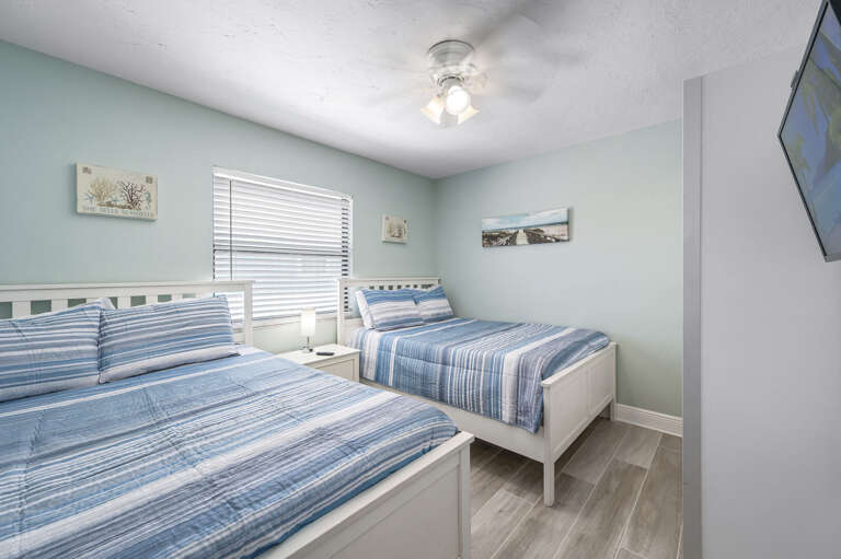 Wake up in the Double bedroom to salt air and coastal art — two beds, a ceiling fan, and a reminder of exactly where you are.