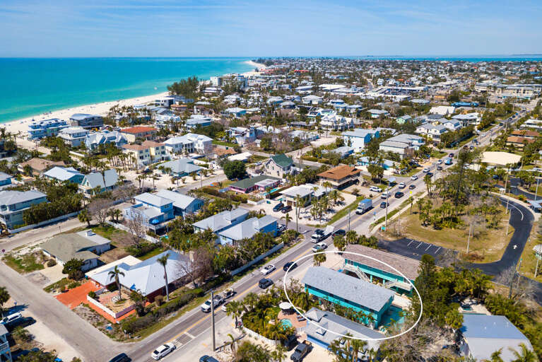 Get your bearings from above — clear turquoise Gulf water to the left, your property right below. The beach is right there whenever you want it.