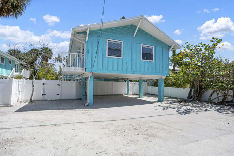 Find your home for the week — teal siding, carport underneath, palm trees on either side. You'll spot it immediately when you pull in.
