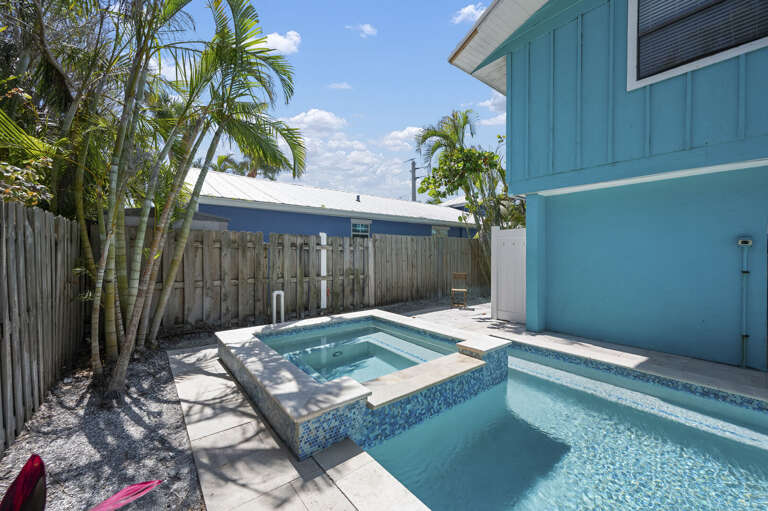 Soak in this — blue mosaic tile, jets running, palms overhead. This is how you end a long beach day.