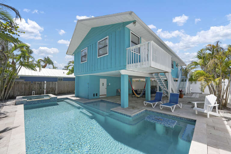 Step back and take it all in — the teal house, the heated pool, the hot tub, and the hammock strung up in the shade. This is the full picture of your week on Anna Maria.