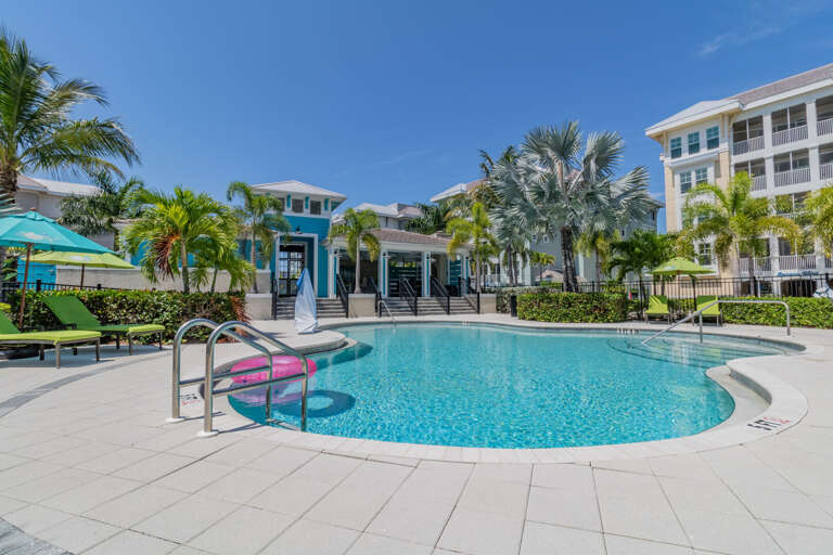 Splash into a resort-style heated pool steps from your front door — sun loungers, palm trees, and blue water waiting.