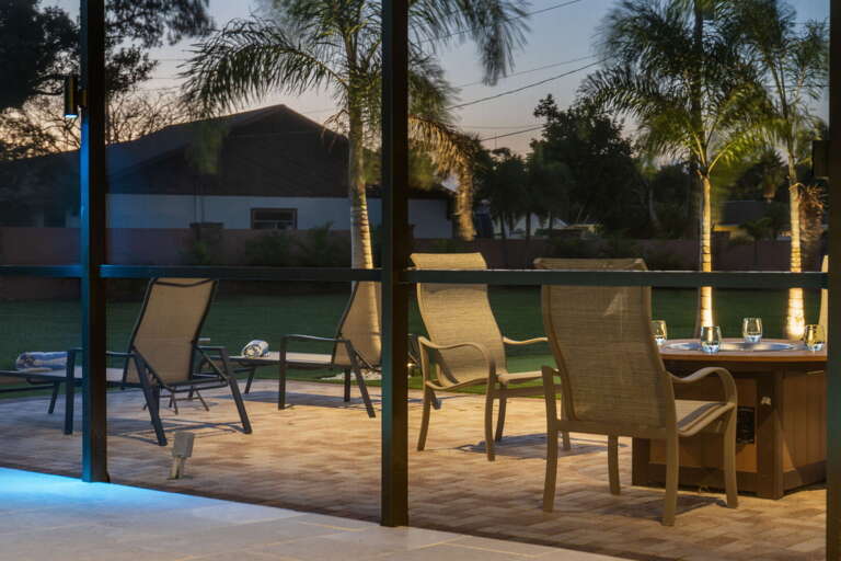 Take in the deck through the screen at dusk — drinks already poured, dinner not yet started, the best half-hour of the day.