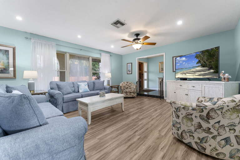 Drop your bags, claim your seat on the blue sofa, ceiling fan on, big TV ready for the next round of family movie night.