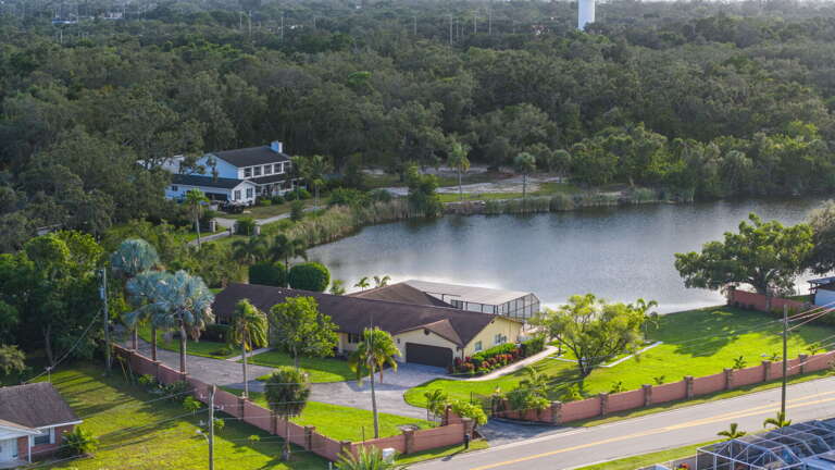 See the gated property from above — tucked into mature trees, the privacy claim proven from the air.