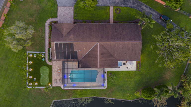 Your private acre from above — gated drive, screened pool, putting green, lake at the back. Everything you came for, all on one lot.