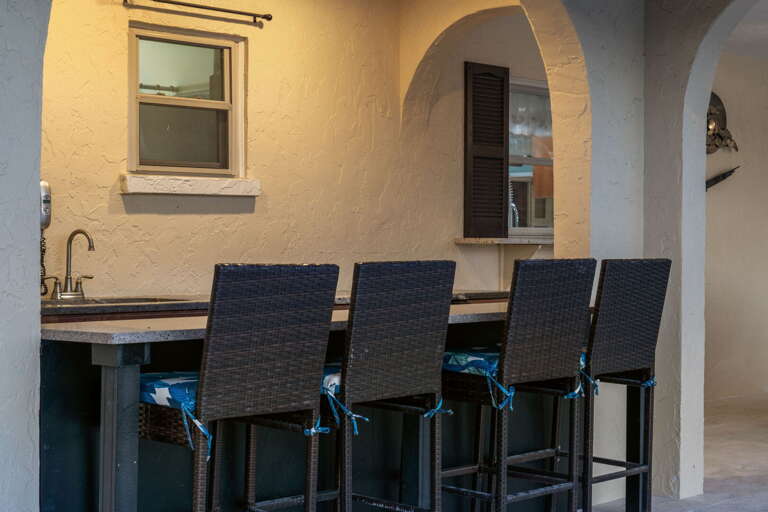 Pull a stool at the outdoor kitchen bar — between the pool and the kitchen, drinks happen naturally here.