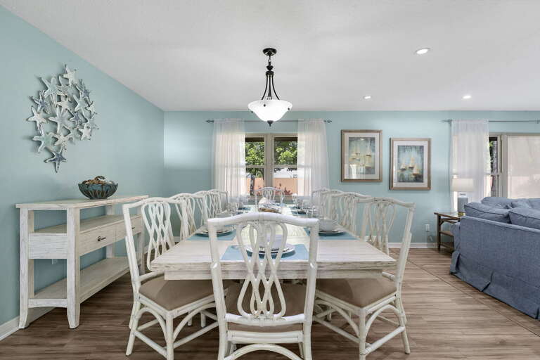 Your sailboat-art dinner corner — wine on the table, eight chairs, the kind of night that runs long.