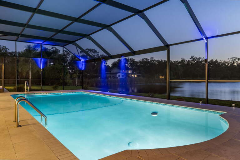 Settle into the lounger after dark — pool lit, screen framing the lake instead of blocking it.