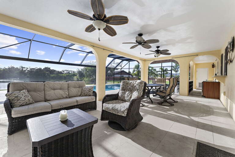 Sink into the wicker sectional on the lanai — the in-between space where afternoons get long and nobody wants to leave.