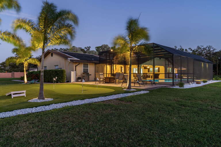 Step onto the lawn at dusk — interior glow through the screen, lake going quiet behind you. This is yours.