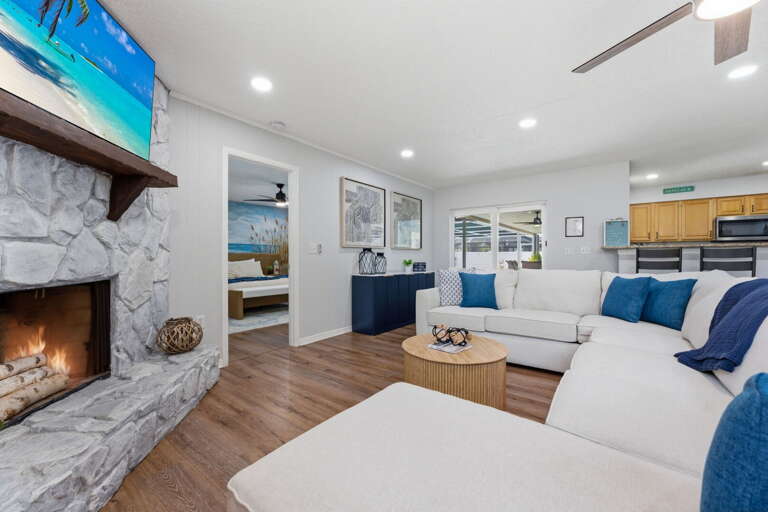 Find your spot on the sofa facing the stone fireplace — the TV is mounted, the fire is glowing, and the evening is completely yours.