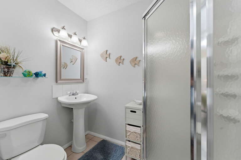 Pedestal sink, glass shower stall, and everything you need for a quick fresh-up before heading out.