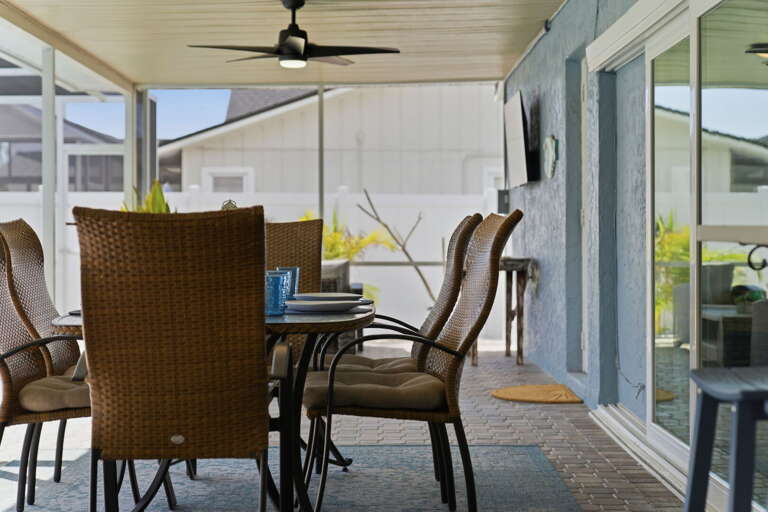 Pull a rattan chair to the screened pool enclosure and sit beside the water with your meal — this is the outdoor dining moment guests mention every time.