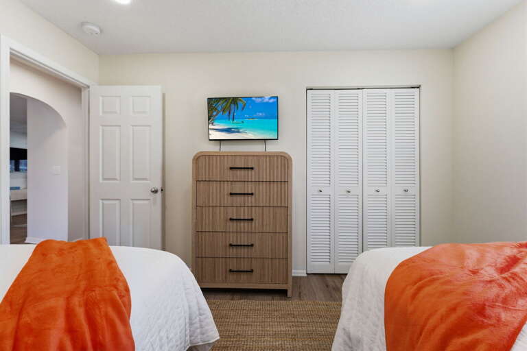 Set up the two-bed room for the second couple or older kids — closet doors, a mounted TV, and a quiet corner of the house just for you.