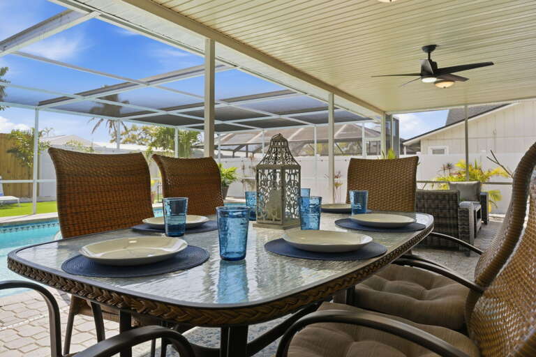Set the outdoor table with the plates and blue glasses waiting there — poolside dinners come together without any effort on your part.