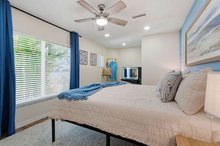 Settle into the corner bedroom with the curtains drawn — the white bed and blue throw make this quiet end of the house an easy place to sleep in.