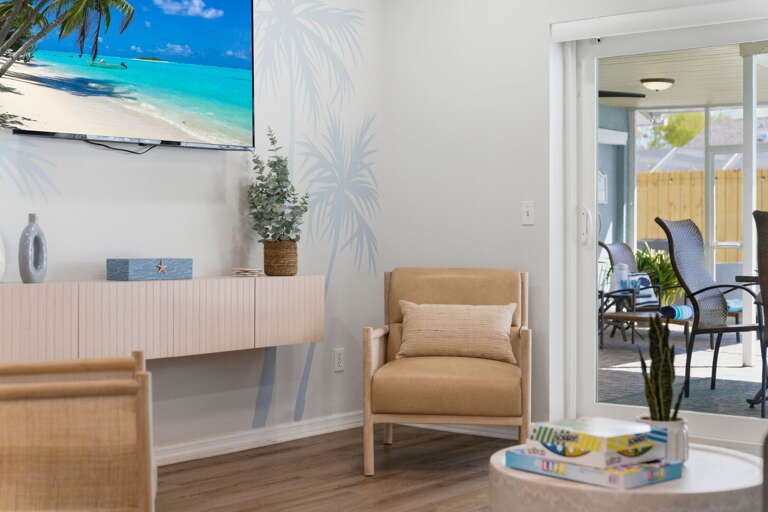 Sink into the armchair with ocean art on the wall and the backyard beyond — the living room is as comfortable as it looks.