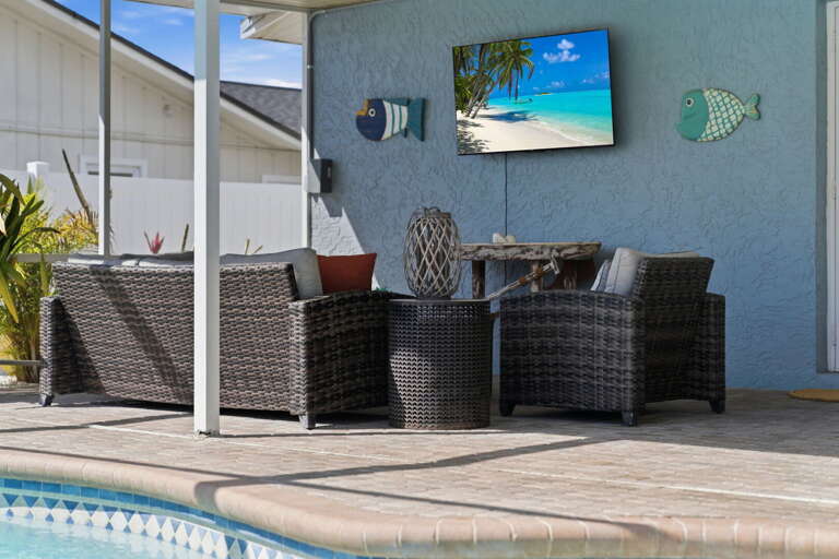 Sink into the outdoor sectional and watch the game on the lanai TV — the screened pool lounge puts you right at water's edge.