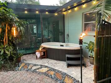 Soak until your shoulders finally drop — the private hot tub fits two and sits tucked in a tropical corner that feels like it's yours alone.